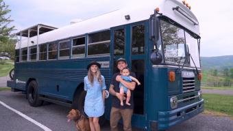 family in front of converted school bus tiny home