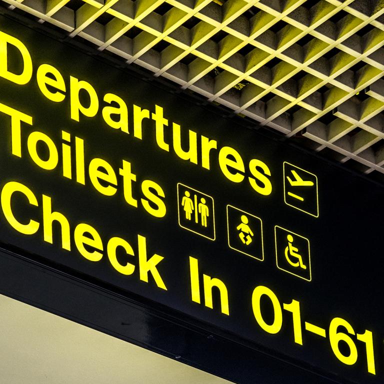 Airport sign with arrows directing to departures, toilets and check in