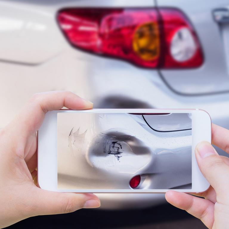 person using smartphone to photograph damage to car