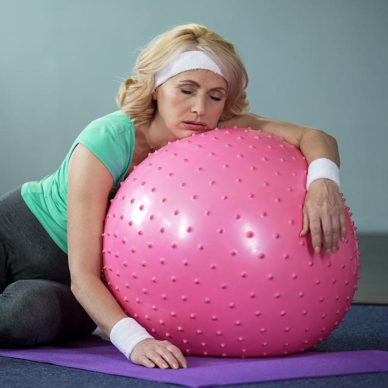 exhausted woman lying on exercise ball