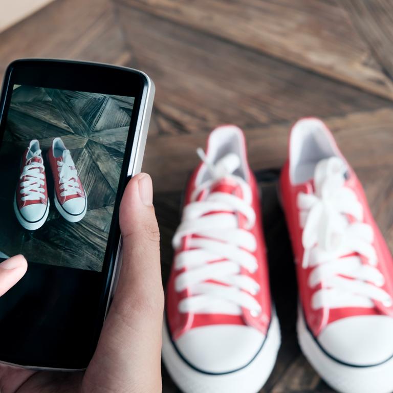 hands using a smartphone to photograph a pair of shoes