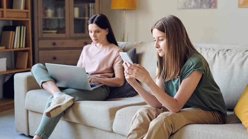 mom and daughter sitting on couch on devices
